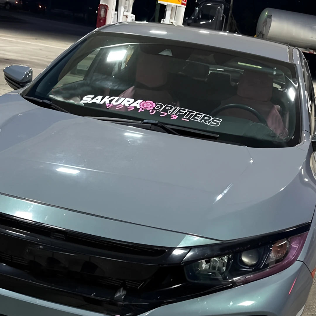 Sakura Drifters windshield sticker with pink cherry blossom design on a black modified car