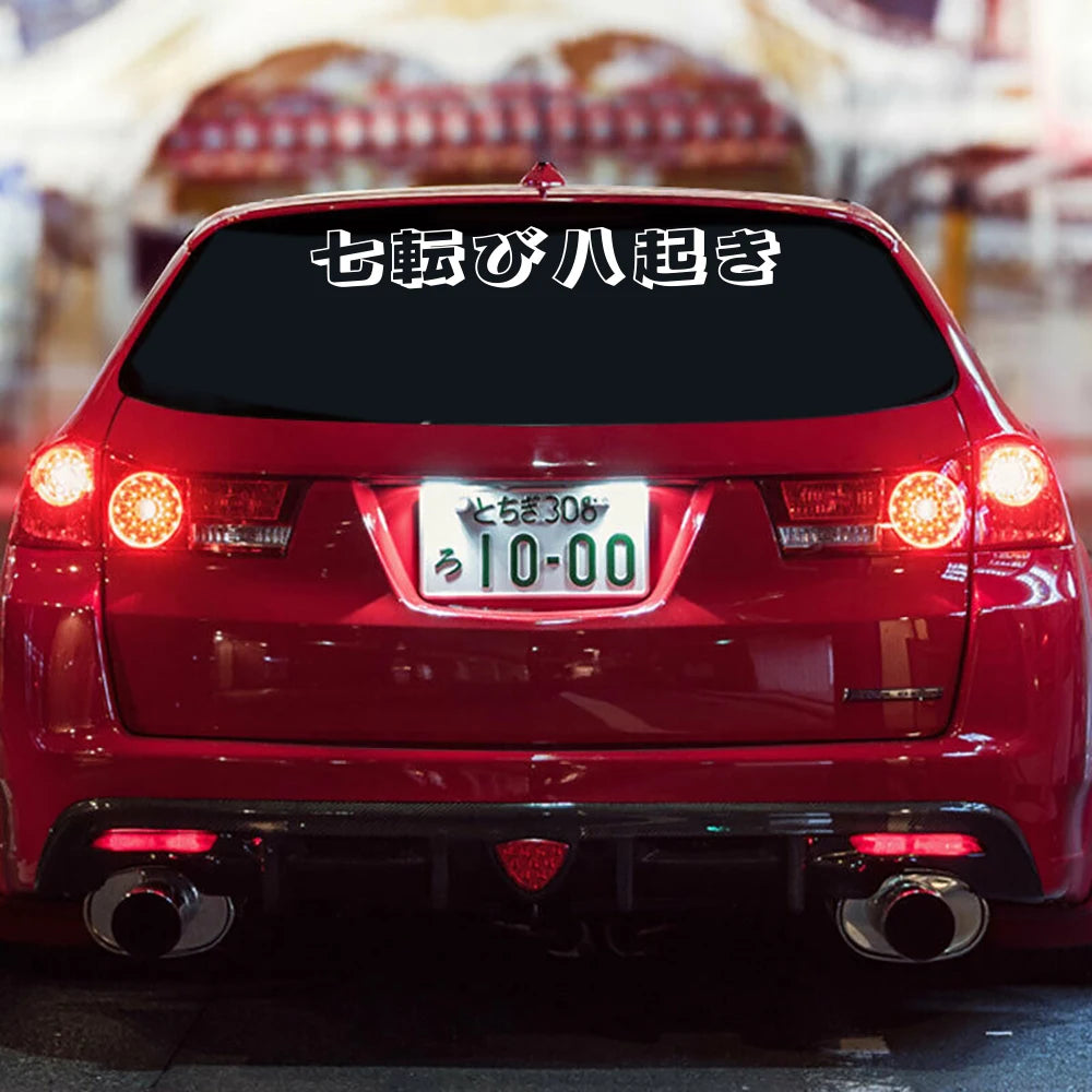 Japanese 七転び八起き windshield sticker displayed on a red modified sports car